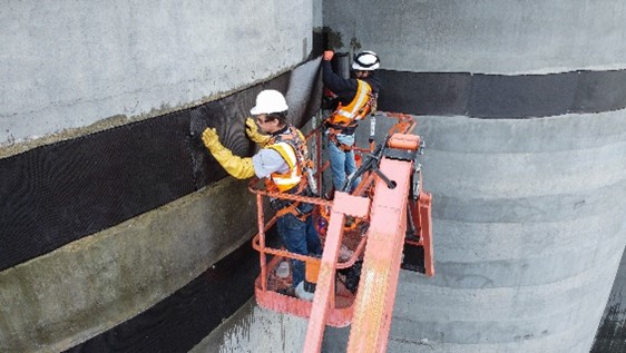 Worker installing carbon fiber straps around concrete columns